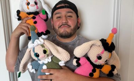 Person holding three colorful knitted animal toys, standing against a plain white wall.