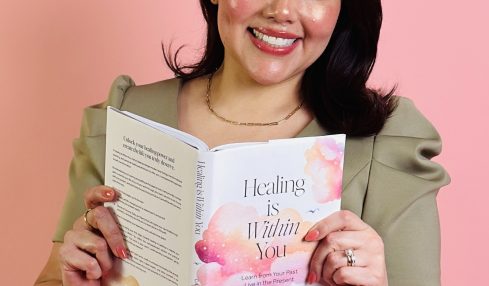 Smiling woman holding a book titled 'Healing is Within You' against a pink background.