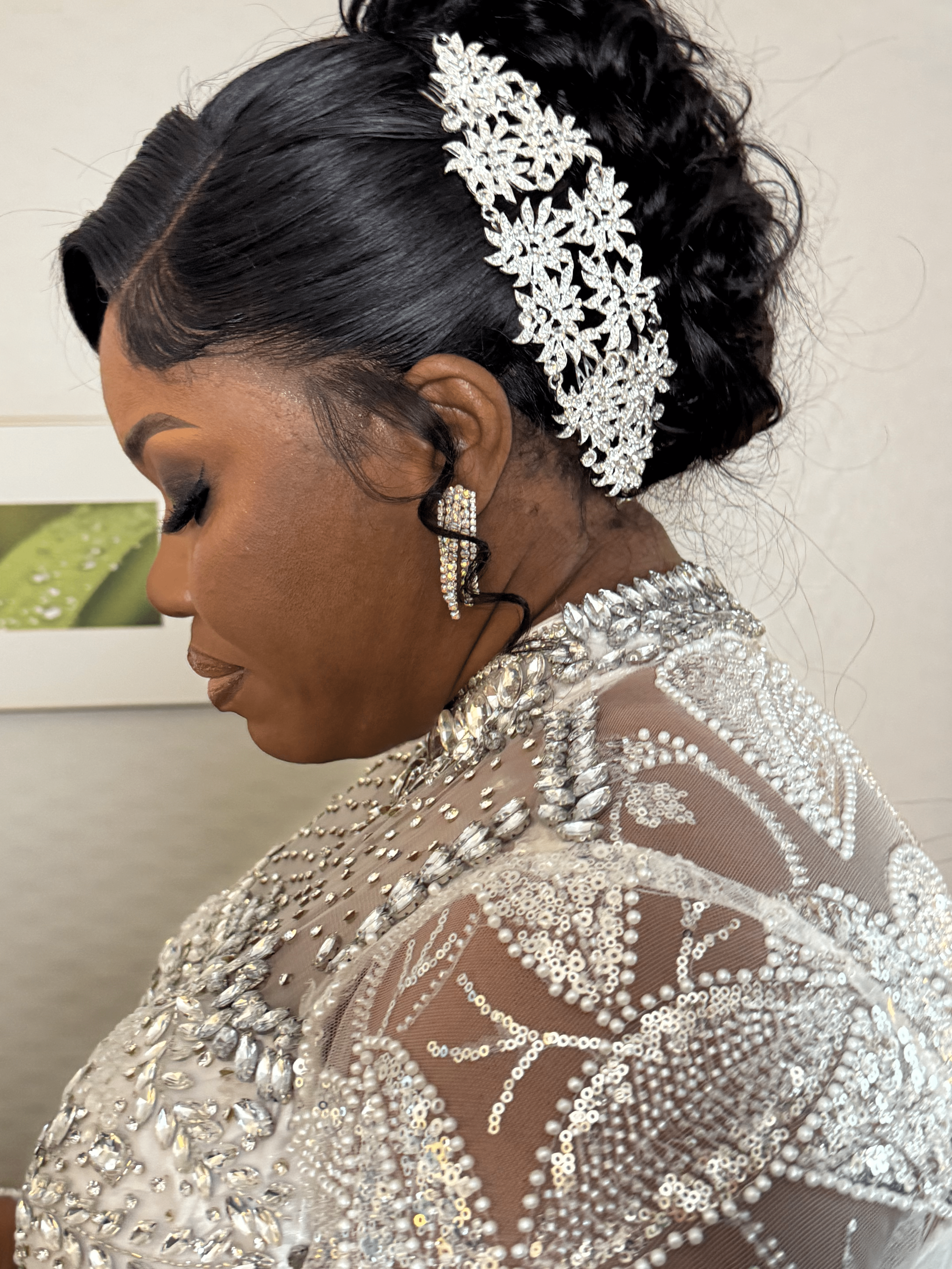 Side profile of a woman with styled hair, wearing a decorative headpiece and ornate dress with beadwork.